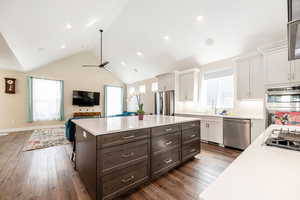 Kitchen with open floor plan, a center island, two tone cabinetry, stainless steel appliances, and dark wood-style floors