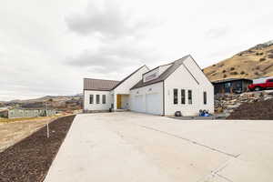 Modern farmhouse featuring a mountain view, a metal roof, concrete driveway, and an attached garage