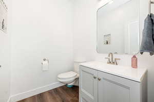 Half bathroom featuring vanity and dark wood-type flooring