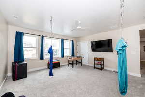 Rec room with light colored carpet, ceiling fan, and a textured ceiling