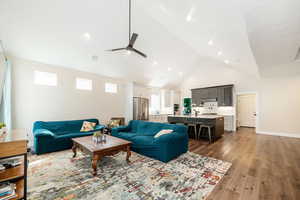 Living area featuring dark wood-type flooring, a high ceiling, and a ceiling fan
