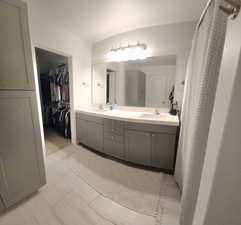 Full bathroom featuring double vanity, a walk in closet, and light wood-style flooring