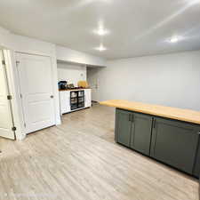 Bar featuring butcher block countertops, light wood-style floors, and dual tone cabinets