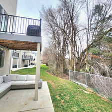 View of green lawn featuring an outdoor hangout area, a patio, and a balcony