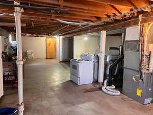 Unfinished basement featuring washer / dryer and heating unit