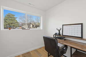 Home office with light wood-style floors and vaulted ceiling