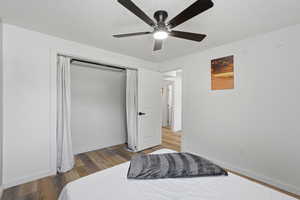 Bedroom with light wood-style flooring, ceiling fan, and a textured ceiling