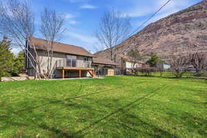 Back of house with a deck with mountain view, stucco siding, and a patio area
