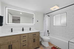 Full bath with double vanity, shower / bath combo with shower curtain, and light wood-type flooring