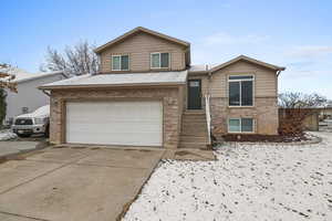 Tri-level home with brick siding, a garage, and concrete driveway