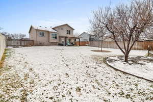 Snow covered back of property featuring a patio and a fenced backyard
