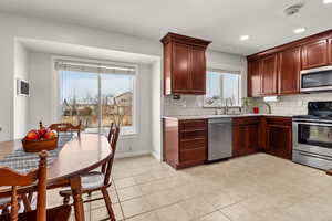Kitchen featuring stainless steel appliances, light stone counters, light tile patterned floors, recessed lighting, and tasteful backsplash