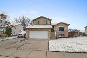 Split level home featuring brick siding, concrete driveway, and an attached garage