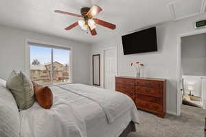 Carpeted bedroom with a ceiling fan and attic access