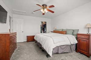 Bedroom with light colored carpet, a ceiling fan, and a spacious closet