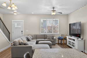 Living room with light wood finished floors, suspended lighting, and a ceiling fan