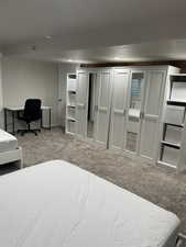 Bedroom with light carpet, an office area, and a closet