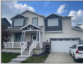 View of front of property with covered porch, stucco siding, concrete driveway, and stone siding