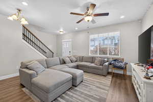 Living room featuring light wood-style flooring, a ceiling fan, and a chandelier