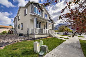 View of side of home featuring a porch, a lawn, and stucco siding