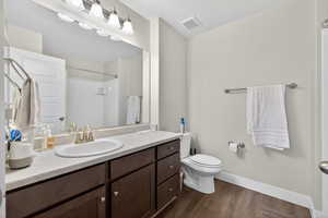 Full bathroom with vanity, dark wood-style floors, and a shower