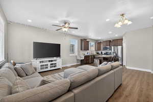 Living room with light wood finished floors, a chandelier, and ceiling fan