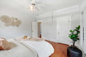 Bedroom with hardwood / wood-style flooring, ornamental molding, and ceiling fan