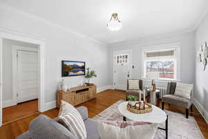 Living room with radiator, wood finished floors, and ornamental molding