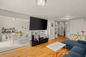 Living room featuring a ceiling fan, light wood-type flooring, and a textured ceiling