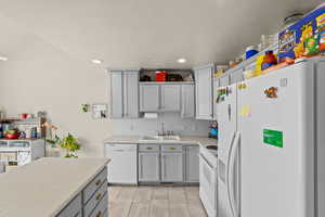 Kitchen featuring gray cabinetry, white appliances, light countertops, tasteful backsplash, and a textured ceiling