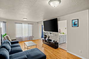 Living room with light wood-type flooring and a textured ceiling