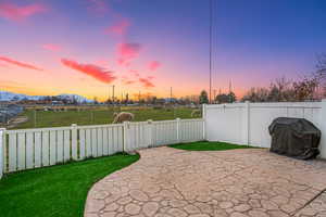 Patio terrace at dusk featuring grilling area, a fenced backyard, a patio area, and a mountain view
