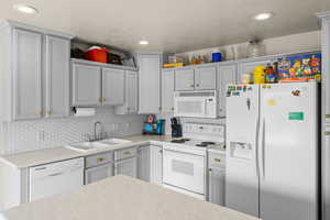 Kitchen featuring white appliances, light countertops, recessed lighting, and tasteful backsplash