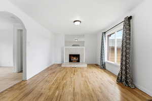 Unfurnished living room with arched walkways, a fireplace, and light wood finished floors