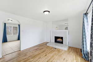 Unfurnished living room featuring light wood-style flooring and a tiled fireplace