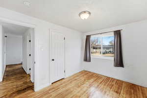 Unfurnished bedroom featuring light wood-type flooring, a closet, and a textured ceiling