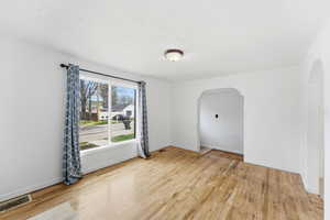 Unfurnished room featuring light wood-style floors and arched walkways