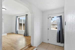 Foyer with arched walkways, light tile patterned floors, and a textured ceiling