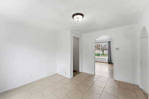 Unfurnished room featuring arched walkways and light tile patterned floors