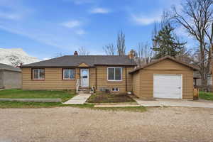 View of front of property with driveway, a garage, a chimney, a mountain view, and a shingled roof