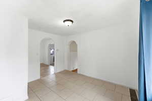 Empty room featuring light tile patterned floors and arched walkways