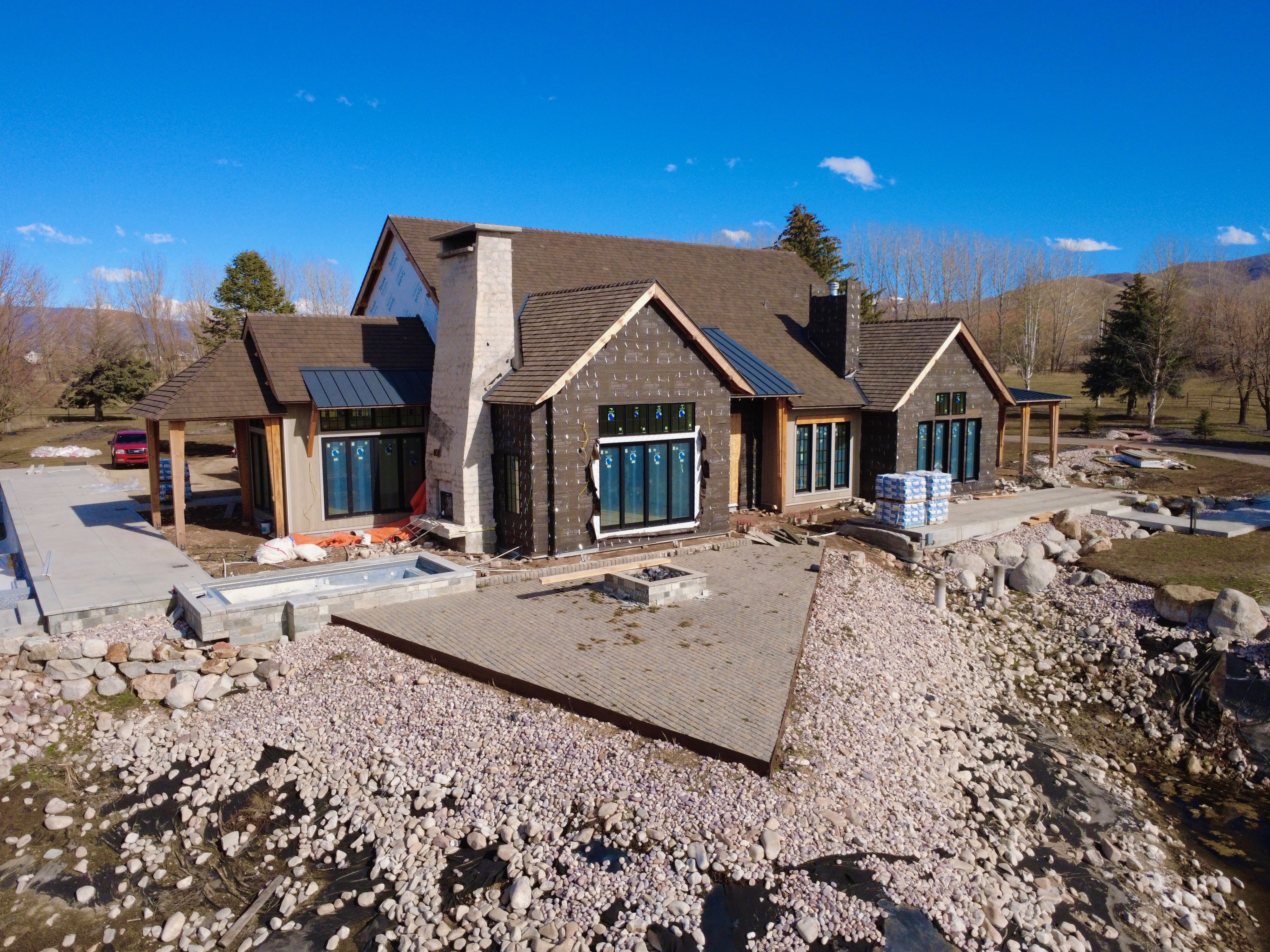 View of front facade featuring a patio, a chimney, and a standing seam roof