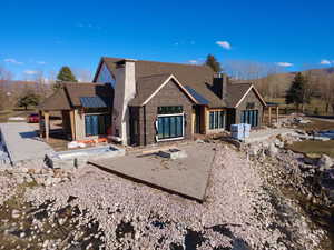 View of front facade featuring a patio, a chimney, and a standing seam roof