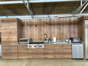 Kitchen with modern cabinets, concrete floors, stainless steel appliances, wooden walls, and wood finish cabinetry