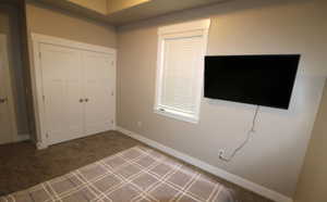 2nd Bedroom with a tray ceiling and dark colored carpet