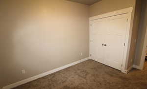 3rd bedroom with dark colored carpet and baseboards