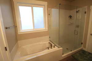 Owners' suite bathroom featuring a double vanity, dark wood-type flooring, and a separate shower and garden tub