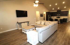 Great room with dark wood-style flooring, lofted ceiling, ceiling fan, recessed lighting, and gas fireplace.