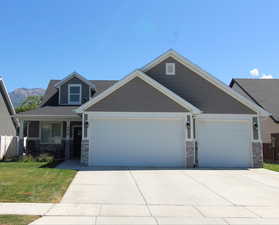 Craftsman-style house featuring stone siding, an attached 2-car garage, a concrete driveway, and a covered porch