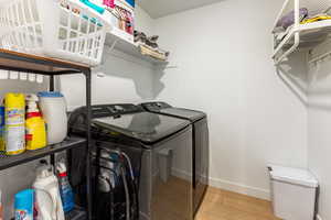 Laundry room with light wood finished floors and washing machine and dryer